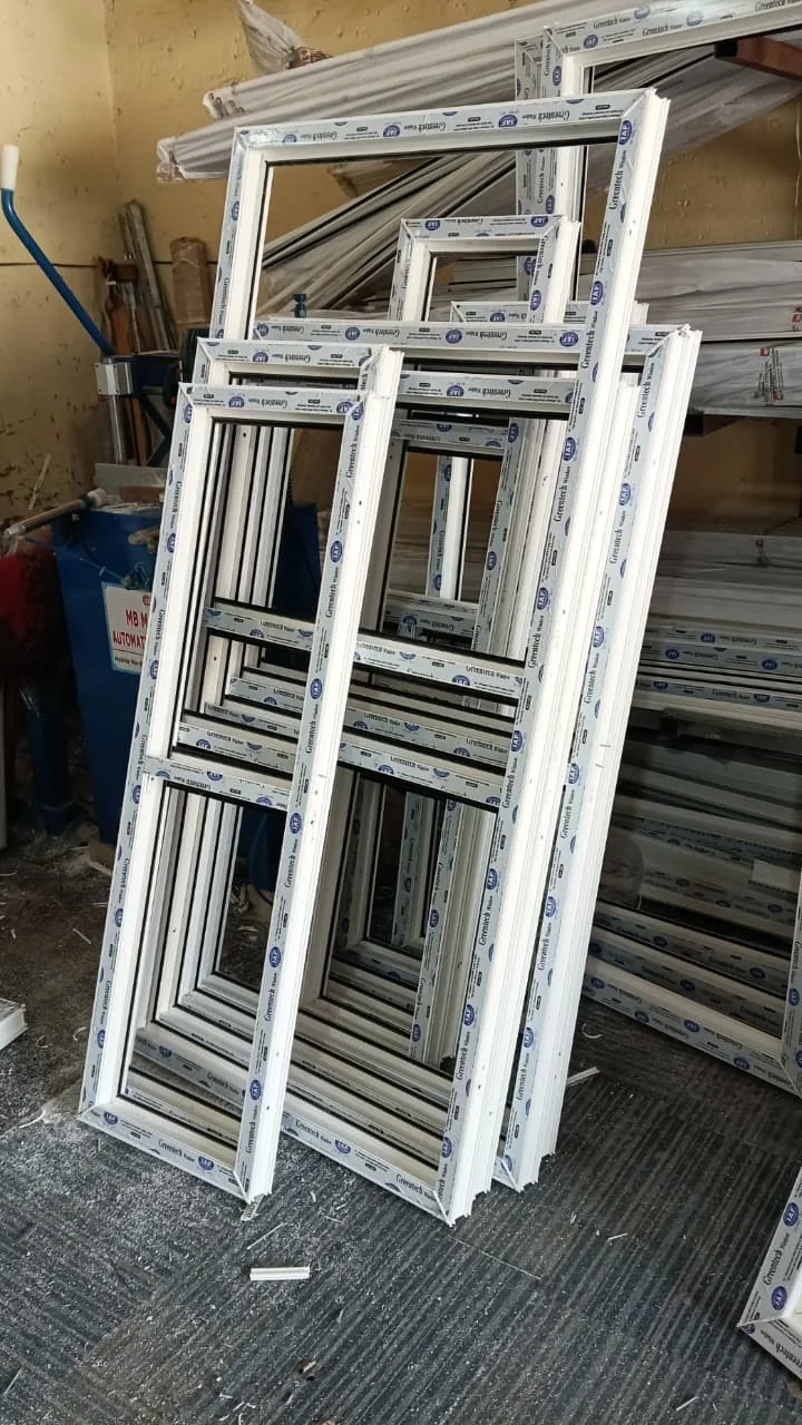 Fabricated uPVC frames stacked in workshop.